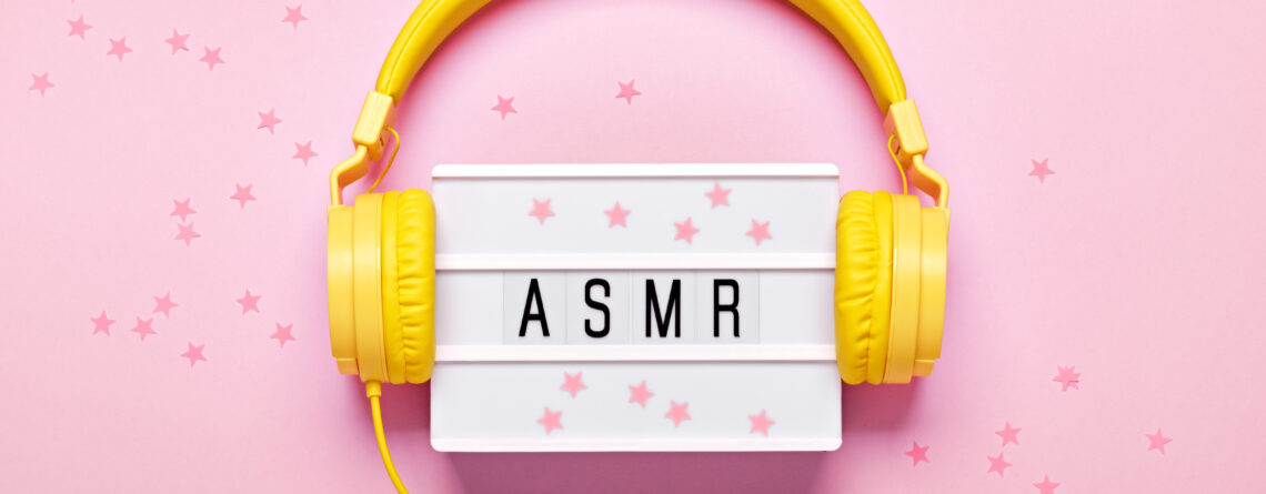 Yellow headphones, ASMR letters lightbox and confetti on pink background. ASMR Stress-relieving sounds concept, flat lay.
