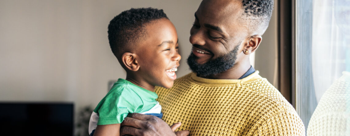 Portrait of a father holding his little son smiling and having fun while experiencing parenthood