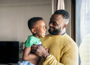 Portrait of a father holding his little son smiling and having fun while experiencing parenthood