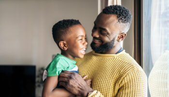 Portrait of a father holding his little son smiling and having fun while experiencing parenthood