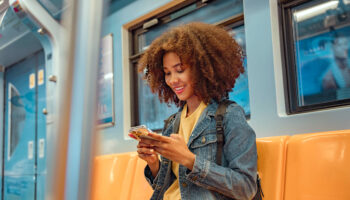 Woman using smartphone for Artificial Intelligence (AI) therapy session while commuting on public transportation