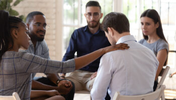 man in white shirt getting support from counselor and outpatient group for addiction to a substance